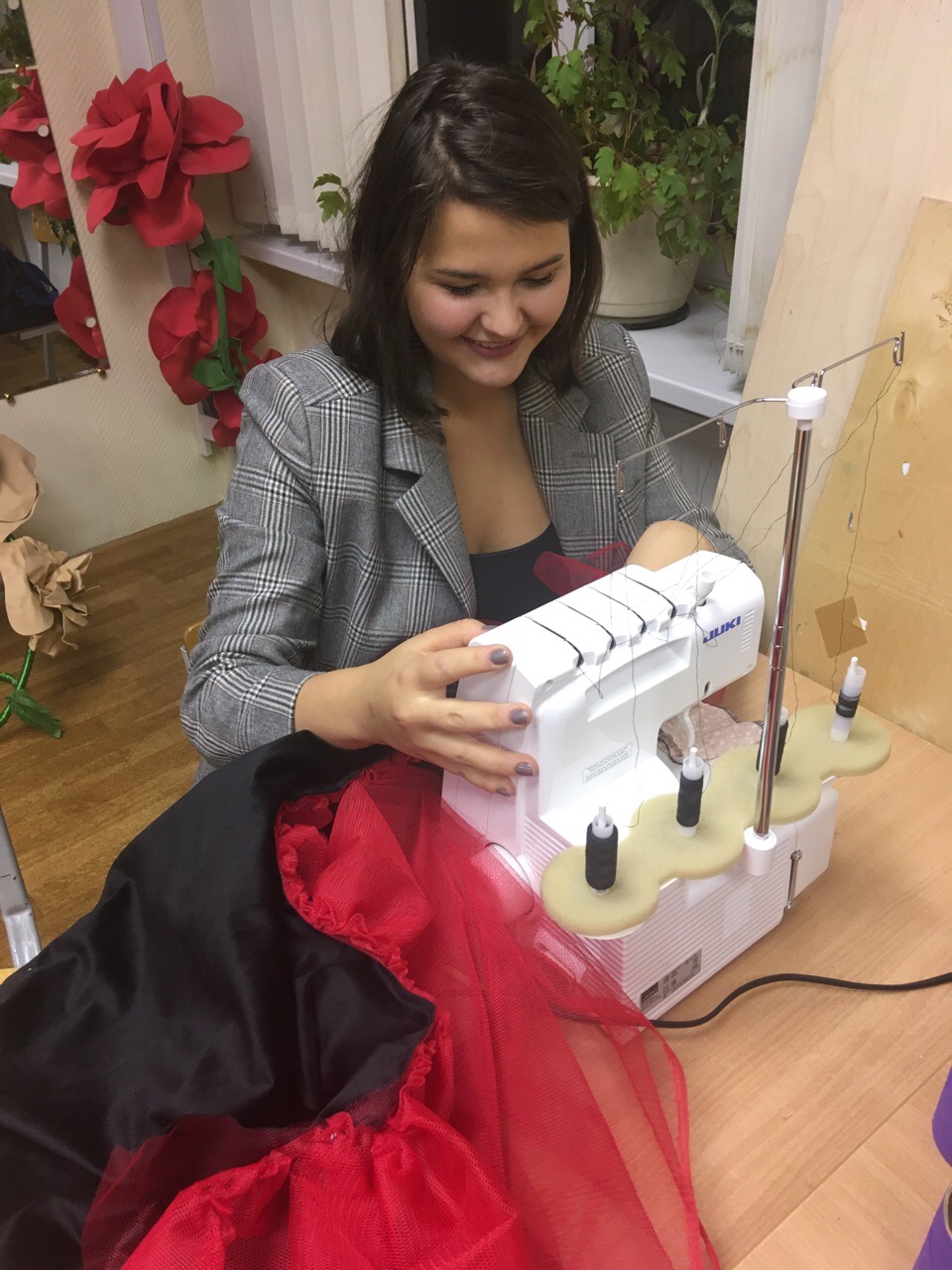 Участница работает на оверлоке с красной тканью